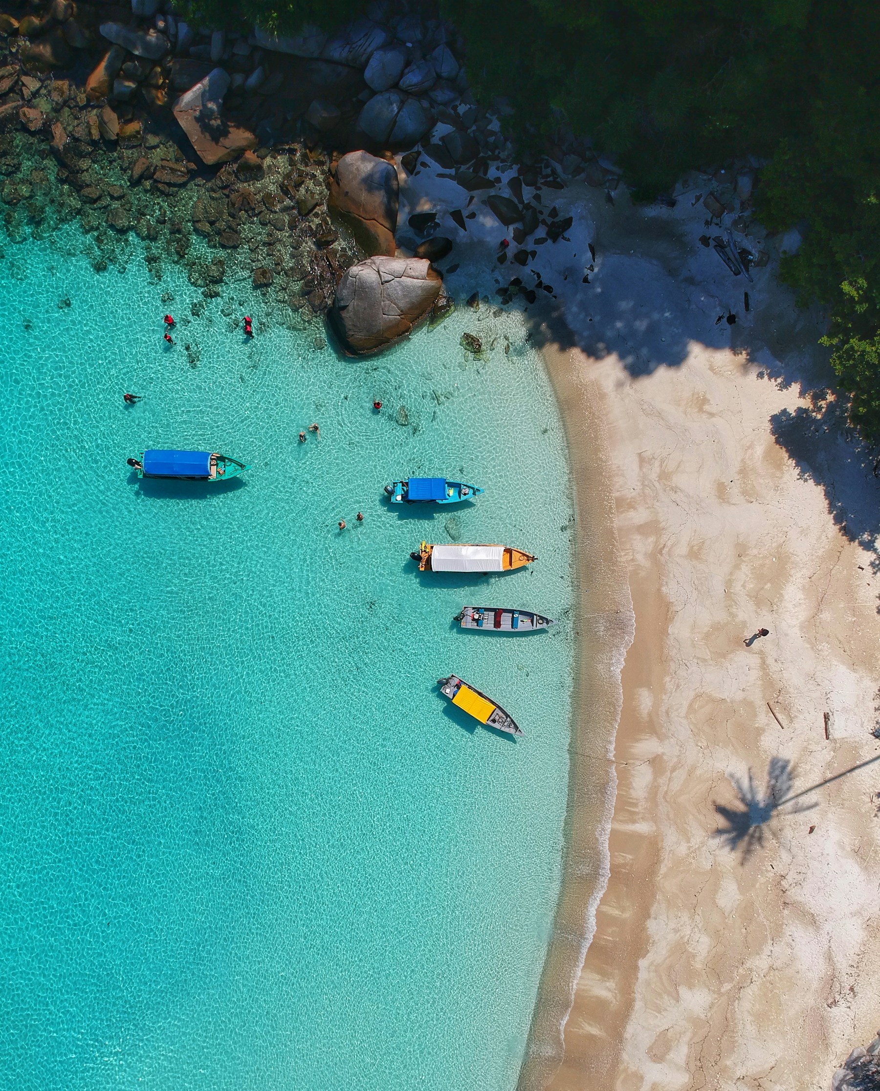 Turquoise water meeting a quiet sandy beach, seen from above